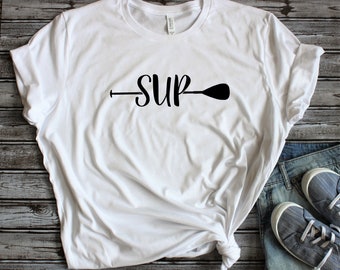May include: White t-shirt with a black graphic of a paddle and the word "SUP" on it.