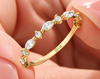 May include: A 14K gold ring featuring a delicate band set with alternating marquise-cut and round-cut clear stones. The inner surface of the gold band is clearly engraved with the text 14K, indicating the metal purity of the jewelry piece.