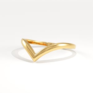 May include: A gold-colored ring with a V-shaped design. The ring is made of a shiny, reflective metal and is set against a white background. The ring's design is simple and elegant.
