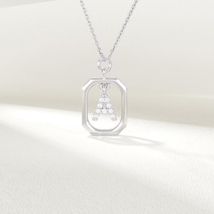 May include: Silver pendant necklace with the letter "A" formed from clear gemstones. The letter is set within a rectangular frame, suspended from a fine chain. The jewellery is presented against a soft, neutral background.