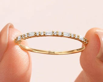 Könnte beinhalten: Ein dünner 14K Goldring mit einem zarten Band, das mit abwechselnden Baguette- und Rundschliff-Steinen besetzt ist. Auf der Innenseite des Rings ist deutlich der Schriftzug 14K eingraviert, der den Goldgehalt dieses Schmuckstücks angibt.