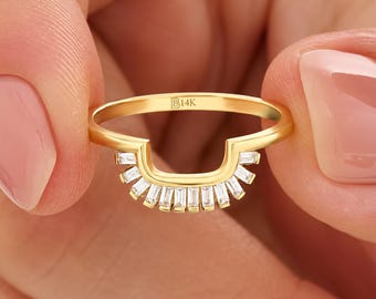 May include: A gold ring featuring a curved, open-frame design adorned with a series of clear, baguette-cut stones arranged in a fan-like pattern. The inner band is engraved with the text B14K, indicating the gold purity of the metal.