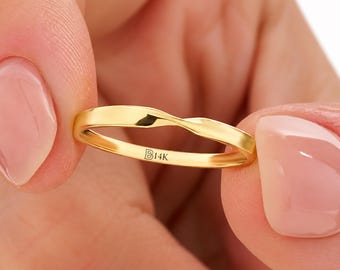 May include: A polished yellow gold ring featuring a subtle twisted design at the top. The inner band is clearly engraved with the text B14K, indicating the metal purity. The ring has a smooth, reflective surface and a continuous, slender band.