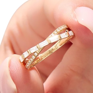 May include: A gold ring with a crisscross design. One band is set with small, round diamonds, and the other features rectangular-cut stones. The ring is marked with "14K".