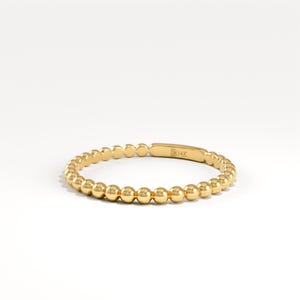 May include: A gold ring featuring a beaded design. The ring is made of gold and has a series of small, round beads that encircle the band. The ring is marked with "14K".
