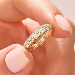 Könnte beinhalten: Ein goldener Ring mit Pavé-Fassung, bei dem zahlreiche kleine, klare, rund geschliffene Steine die Außenfläche bedecken. Auf der Innenseite des Rings ist deutlich der Text 14K eingeprägt, der den Goldgehalt des Schmuckstücks angibt.