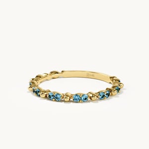Könnte beinhalten: Ein 14K Goldring mit einer Reihe kleiner, runder, leuchtend blauer Edelsteine, die in einem sich wiederholenden Muster mit glatten Goldperlen dazwischen angeordnet sind. Die Innenseite des Rings ist mit dem Text 14K gestempelt.