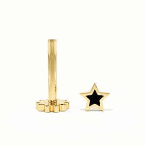 May include: A gold-toned flat back stud earring featuring a star-shaped top with a black inlay. The piece consists of a smooth, cylindrical post attached to a gear-shaped base, displayed alongside a separate star-shaped component with black center.