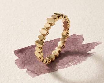 May include: A yellow gold ring featuring a series of connected, polished circular discs of varying sizes arranged in a continuous band. The metal surface is smooth and reflective, with a small 14K hallmark visible on the inner side of the band.