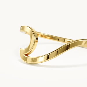 Peut inclure: Une bague en or poli présentant un design fluide et continu en forme de vague. L'anneau se courbe pour former une crête stylisée proéminente qui imite la forme d'une vague déferlante, avec une surface métallique lisse et très réfléchissante.
