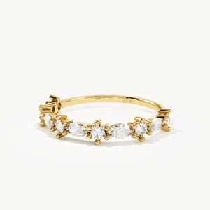 May include: A 14k yellow gold ring featuring a delicate band set with alternating marquise-cut and round-cut clear stones. The stones are arranged in a repeating pattern along the front half of the band, which is stamped with 14k on the interior.