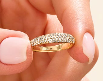 May include: A gold band ring featuring a pavé setting of numerous small, clear, round-cut stones across the top surface. The interior of the polished gold band is clearly engraved with the text B14K, indicating the metal purity.