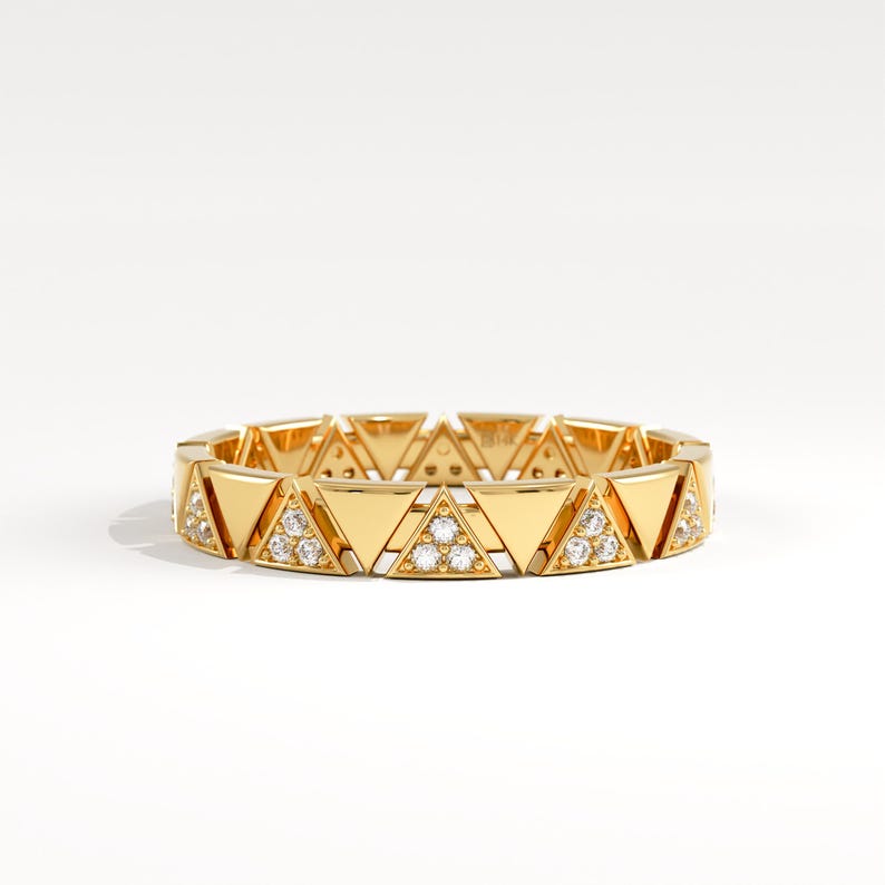 May include: A gold ring with a repeating triangular design. Each triangle is set with small gemstones. The ring has a polished finish and a contemporary, geometric style. The design is suitable for everyday wear or special occasions.
