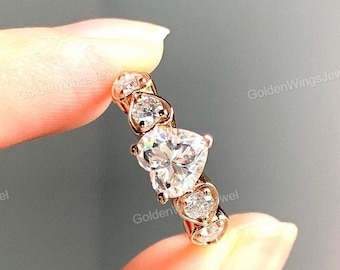 Op de afbeelding: Een ring van roségoud met een grote hartvormige diamant en kleinere diamanten die in een band zijn gezet.
