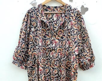May include: A long, flowing dress with a floral pattern in black, red, and tan. The dress has a collared neckline, button details, and three-quarter sleeves. It is hanging on a wooden hanger.