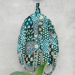 May include: A green patchwork backpack with blue, white, and red accents. The backpack has a zipper closure and adjustable straps.