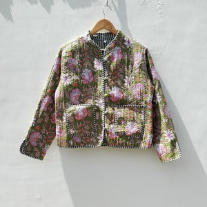 Può includere: Una giacca trapuntata verde con stampa floreale e chiusura con bottone. La giacca ha un colletto alla coreana e due tasche a toppa.