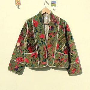 May include: A green quilted jacket with a floral print featuring birds and flowers. The jacket has a white trim and a shawl collar.