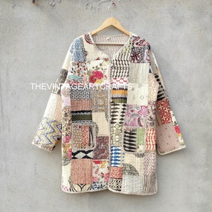 Puede incluir: Una chaqueta acolchada de color crema con un diseño de patchwork que presenta varios colores y patrones. La chaqueta tiene cuello en V y mangas largas.