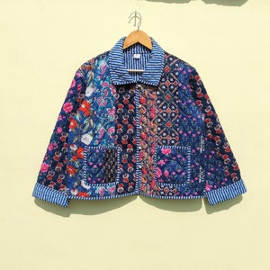 May include: A blue quilted jacket with a floral patchwork design. The jacket has a button-up front, a collar, and two pockets.