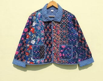 May include: A blue quilted jacket with a floral patchwork design. The jacket has a button-up front, a collar, and two pockets.