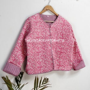 Pode incluir: Uma jaqueta acolchoada rosa com estampa floral branca e fecho de botão. A jaqueta tem forro e punhos listrados.