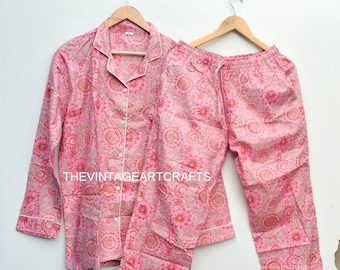 May include: Pink cotton pajama set with a floral print. The top has long sleeves and a button-up front. The pants have an elastic waistband and a drawstring.