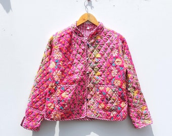 May include: A pink quilted jacket with a floral print and a button closure. The jacket has a stand-up collar and two pockets.