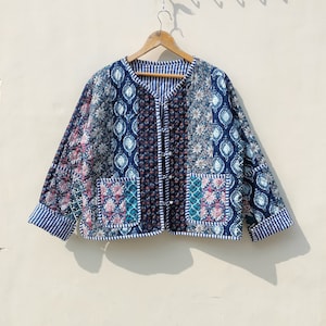 May include: A blue quilted jacket with a patchwork design featuring floral and geometric patterns. The jacket has a button closure and a striped lining.