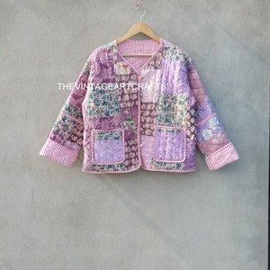 May include: A pink quilted jacket with a floral pattern and a button closure. The jacket has two pockets and a striped lining.