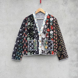 Puede incluir: Una chaqueta acolchada negra con estampado floral y cierre de botones blancos. La chaqueta tiene dos bolsillos de parche en la parte delantera y un forro a rayas blanco y negro.