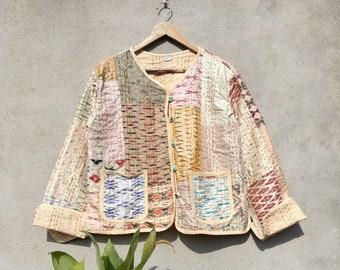 Puede incluir: Una chaqueta acolchada de color crema con un diseño de patchwork. La chaqueta tiene un cierre de botón y dos bolsillos de parche. La tela es una mezcla de beige, marrón, rosa y azul.