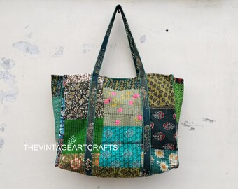 Peut inclure: Un sac cabas en patchwork avec un motif floral vert, bleu et blanc. Le sac a de longues lanières vertes et est fait de tissu matelassé.