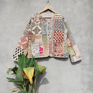 Pode incluir: Uma jaqueta de patchwork com uma variedade de cores e padrões, incluindo vermelho, azul, verde e amarelo. A jaqueta é feita de algodão e tem um fecho de botão.