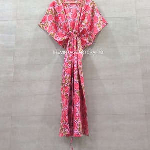 May include: A pink and green floral print kaftan with a deep V-neckline and a tie at the waist. The kaftan has short, wide sleeves and a flowing skirt.
