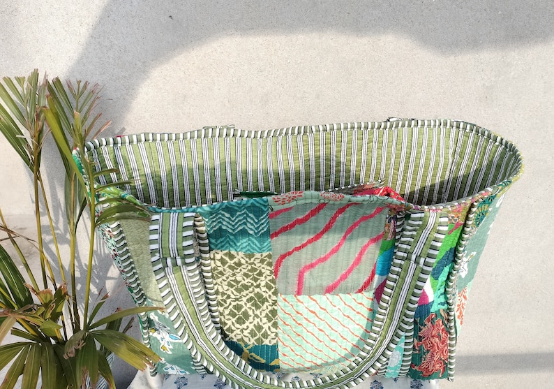 May include: A large green and white striped tote bag made from patchwork fabric. The bag has two handles and is made from a variety of different fabrics, including green, blue, pink, and white.