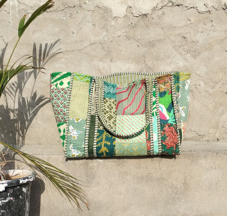 May include: A patchwork tote bag made from different fabrics in shades of green. The bag has a large main compartment and two shorter handles.