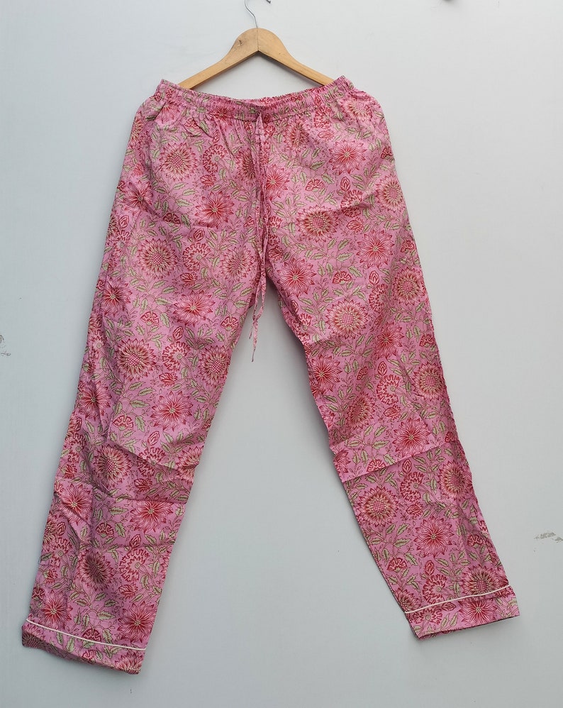 May include: Pink cotton pajama pants with a floral print. The pants have an elastic waistband and a drawstring.