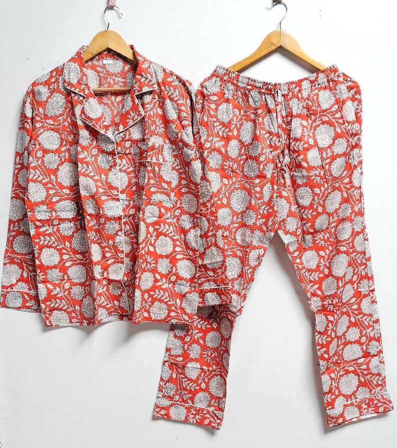 Puede incluir: Un conjunto de pijama de estampado floral rojo y blanco con una parte superior de manga larga y pantalones.