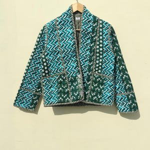 May include: A green and blue quilted jacket with a geometric pattern. The jacket has a collar and a front closure.