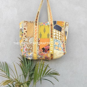 May include: A large yellow patchwork tote bag with a variety of colorful patterns and textures. The bag has long straps and is made of quilted fabric.