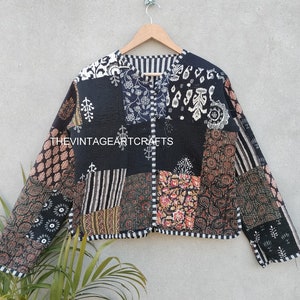 May include: A black quilted jacket with a patchwork design featuring various floral and geometric patterns. The jacket has a button closure and long sleeves.