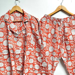 Puede incluir: Un conjunto de pijama de estampado floral rojo y blanco con mangas largas y pantalones.