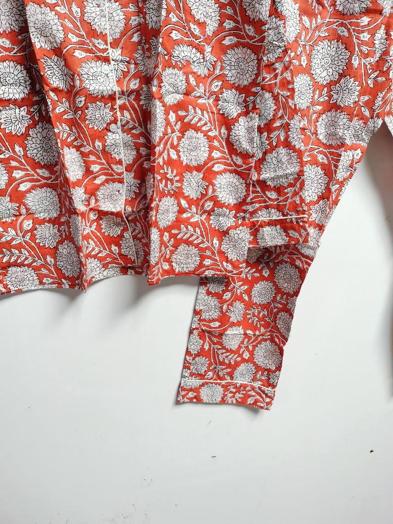 Puede incluir: Una tela de algod&oacute;n roja y blanca con estampado floral. La tela tiene un borde blanco y est&aacute; doblada por la mitad.