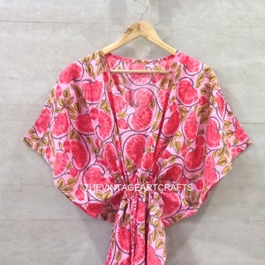 May include: A pink and red floral print kaftan with a V-neck and short sleeves. The kaftan has a tie at the waist and the text "THEVINTAGEARTCRAFTS" is printed on the bottom.