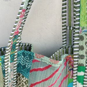 May include: A green patchwork tote bag with white and green striped handles. The bag is made of different fabrics with various patterns, including floral, geometric, and striped.
