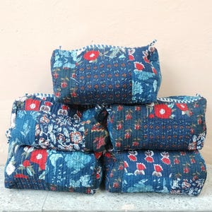 以下が含まれることがあります： 6つのキルト生地ポーチのスタック。各ポーチは、ネイビーブルーの背景と赤い花柄のパッチワークデザインが特徴です。ポーチは長方形で、丸みを帯びたエッジとステッチのボーダーが付いています。