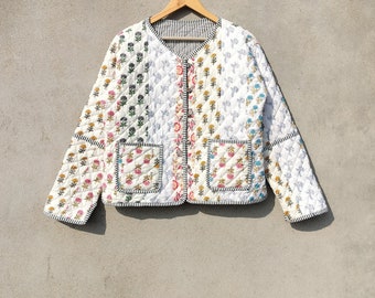 Puede incluir: Una chaqueta acolchada blanca con estampado floral y dos bolsillos de parche. La chaqueta tiene cierre de botón y forro a rayas.