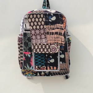 May include: A black and brown patchwork backpack with a white and black trim. The backpack has a large pocket on the front and a smaller pocket on the side.