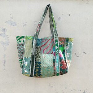 May include: A patchwork tote bag with green, blue, and pink fabric squares. The bag has long straps and a zipper closure.